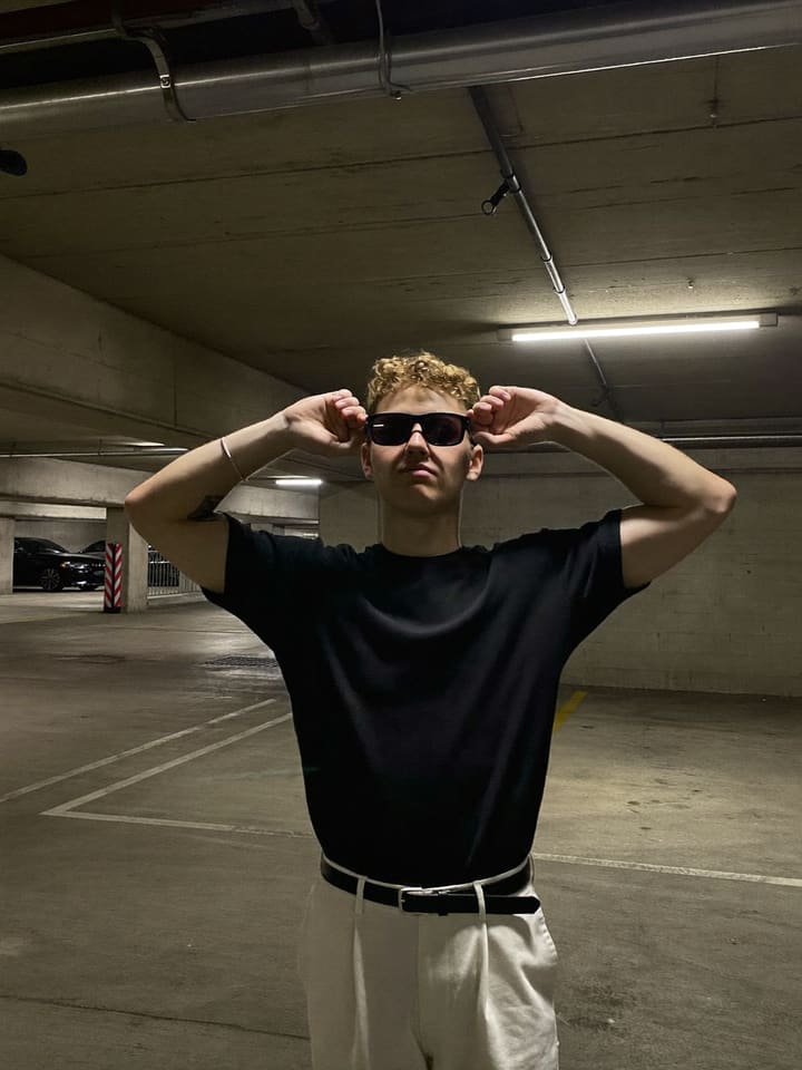 Hand over brow, sunglasses on at Downtown parking structure